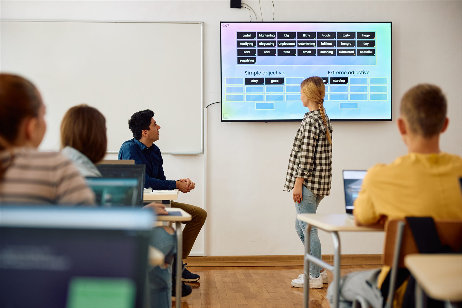 Zespół pracujący przy monitorze interaktywnym w sali szkoleniowej