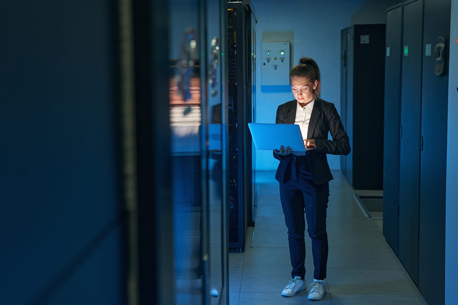 Technik z laptopem przy szafie serwerowej w data center